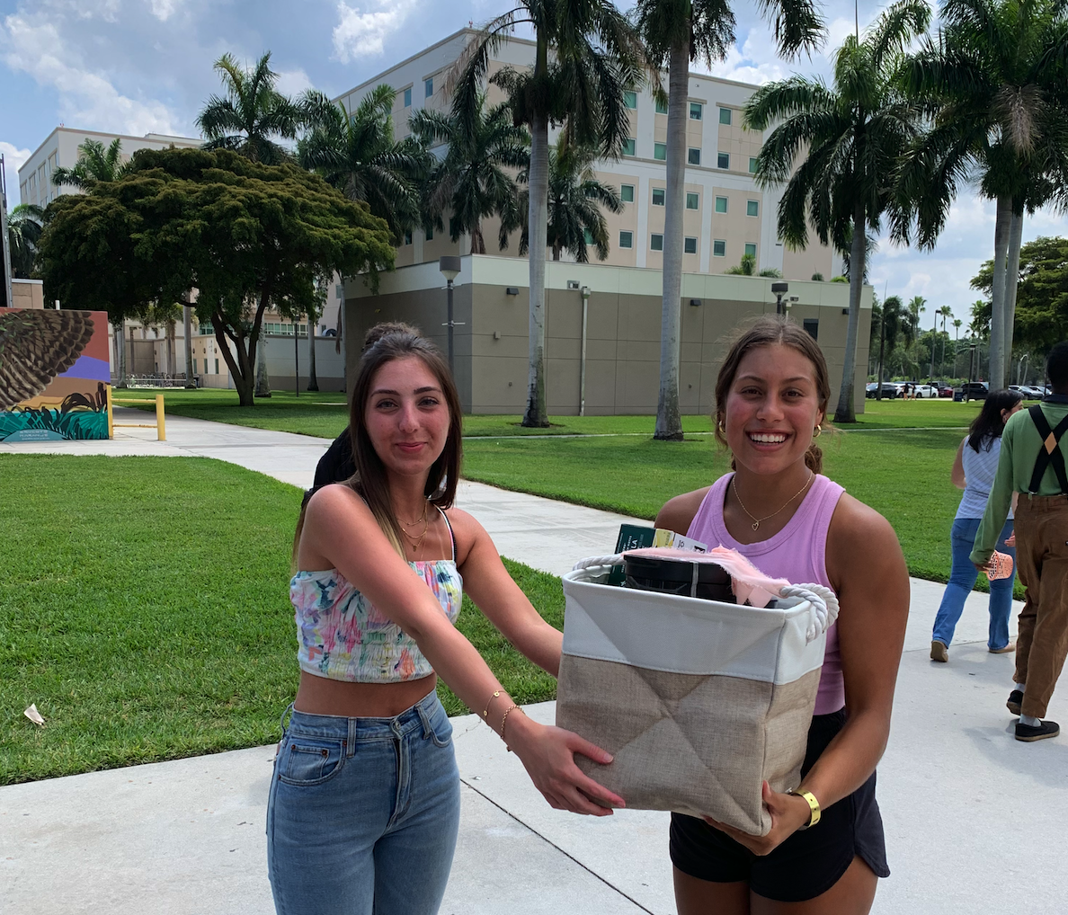 Program board officer Isabella Sanossian (left) awarding Maya Desai (right) her prize for finding the golden ticket.